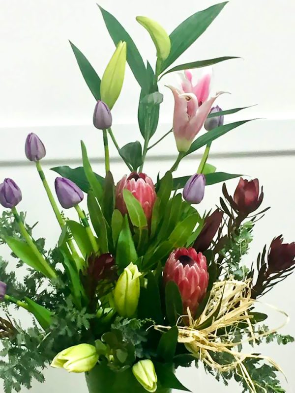 Oriental lilies, pink ice protea, tulips, silvan red and soft grey foliage